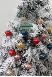 Close-up of colorful Christmas candy pendants with glitter and matte finishes on a snowy tree