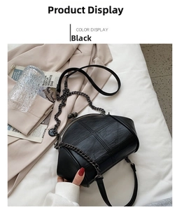 Detail of black quilted cross-body bag with kiss-lock clasp and chain strap