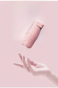 Ultralight pink mini folding umbrella held by a hand to show its compact size