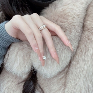 Long almond nude pink press-on nails with sparkling rhinestones and floral 3D nail art decor