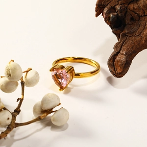 Detailed close-up of a pink heart gemstone ring set in gold on a natural artistic backdrop