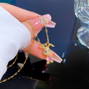 Detail of pink crystal rabbit pendant with white zircon pavé on a golden chain