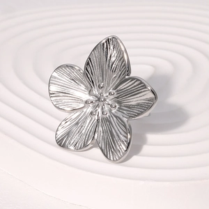 Elegant silver flower ring with textured petals on a minimalist white pedestal base