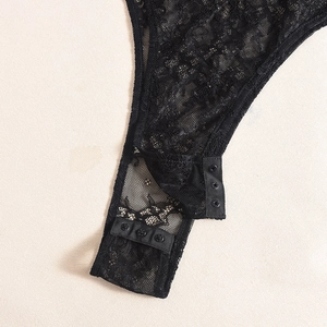 Détail d'un body en dentelle noire avec fermeture à boutons-pression et motifs floraux