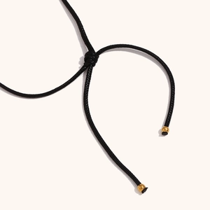 Macro detail of adjustable sliding knot with gold-plated beads on black necklace cord