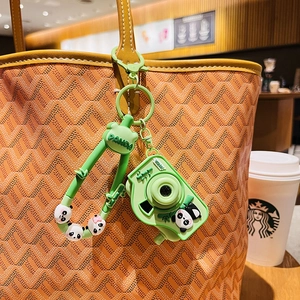 Cute green panda camera keychain with LED projector on a stylish handbag