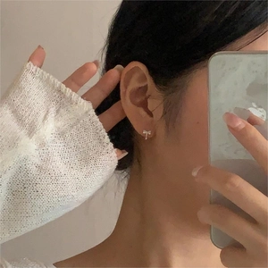Close-up of sparkling 925 sterling silver bow earrings worn by a model in mirror selfie