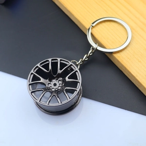Detailed macro view of a glossy dark grey alloy car wheel rim keychain with a flat metal ring