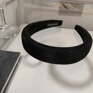 Detail of a handmade thick black headband with sparkling fabric and woven label