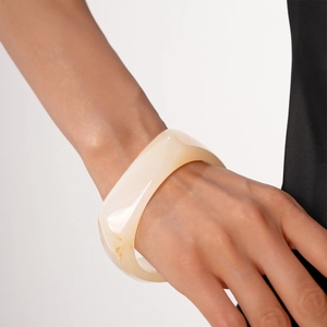 Detail of cream white resin chunky bangle showing smooth geometric texture on wrist