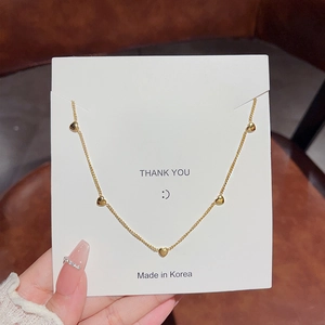 Elegant gold-tone heart tassel necklace with five pendants on a premium jewelry card
