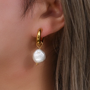 Gros plan de boucles d'oreilles dorées en acier inoxydable avec perles baroques