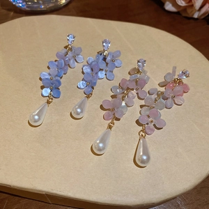 Detail of flower tassel earrings featuring blue resin petals and teardrop pearls