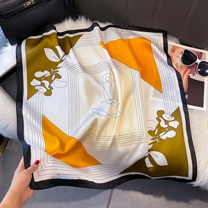 Dettaglio di un foulard quadrato in finta seta con motivi artistici arancioni e verdi