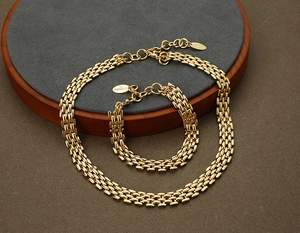 Detail of gold-tone chunky hip-hop necklace and bracelet set on a grey display mat