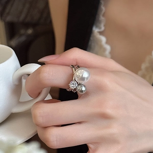 Detail of silver pearl ring with zircon on finger holding a white porcelain cup