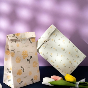 Floral gift bag with circular seal sticker on aesthetic purple background