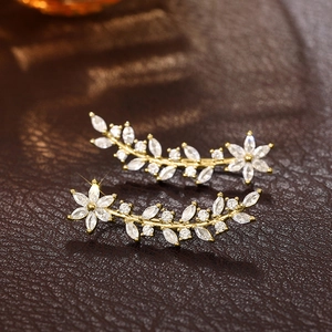 Macro detail of gold flower ear crawler earrings with marquise-cut sparkling zircons