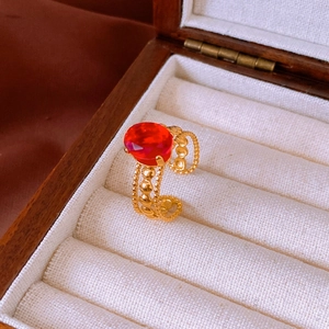 Detail of a vintage gold wavy ring with a red oval gemstone in a wooden jewelry box