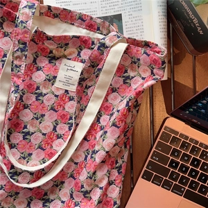 Detail of floral tote bag with rose print and white label on a cozy office desk setting