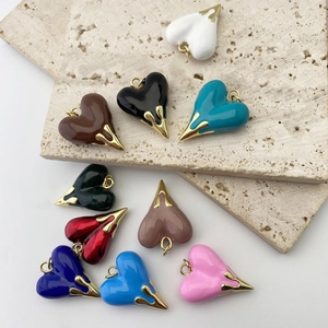 Collection of colorful enamel heart pendants with gold-plated metal loops on stone