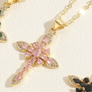 Macro view of gold cross necklace featuring pink pear-cut zircons and shiny finish