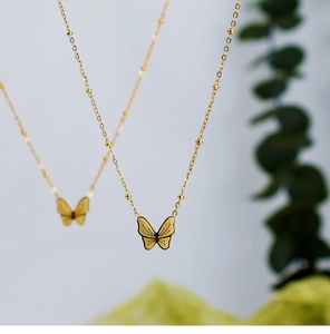 Makroaufnahme einer 18K vergoldeten Schmetterlingskette mit eleganter Perlenkette