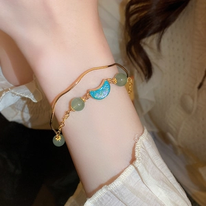Detail of gold-plated freshwater pearl bracelet with green beads and moon pendant