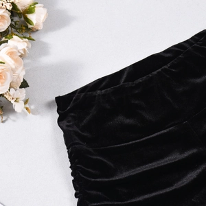 Detailed view of black velvet shorts showing elastic waistband and ruched fabric texture