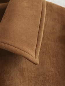 Gros plan détaillé montrant la texture du daim marron et les coutures de la veste