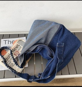 Close-up of a large denim tote bag featuring woven rope straps and metal zipper detail