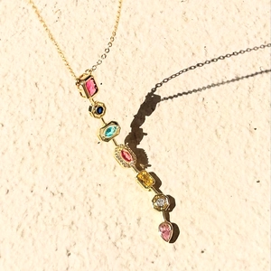 Vertical detail of gold necklace with colorful rectangular and teardrop crystals