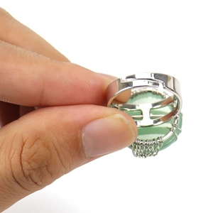 Detail of silver wire wrapped ring with a green gemstone and adjustable open band
