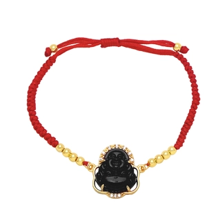 Detail of red braided bracelet featuring a black Buddha pendant with gold diamond accents