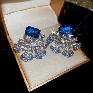 Macro shot of silver fan-shaped earrings with blue gemstones and sparkling diamonds