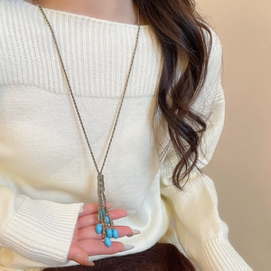 Detail of long bohemian tassel necklace with sky blue beads and woven metal knot detail