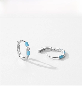 Detailed view of silver hoop earrings with light blue enamel and zircon inlay