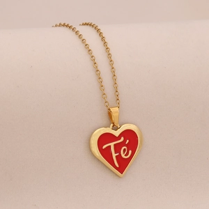Détail du pendentif cœur doré avec émail rouge et inscription Fé sur une chaîne fine