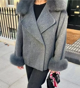 Detail of elegant grey wool coat featuring plush faux fur collar and matching cuffs