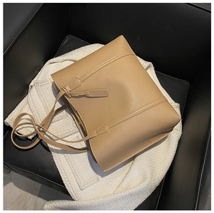 Detailed view of the brown leather tote bag texture resting on a white knitted sweater