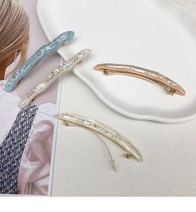 Dettaglio di fermagli per capelli in resina colorata con glitter e base in metallo dorato
