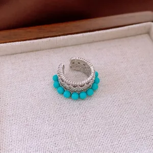 Vintage silver hollow C-shaped ear cuff with blue turquoise beads on fabric display