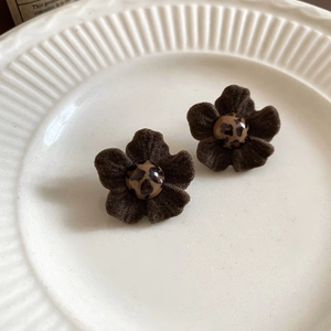 Macro shot of retro floral stud earrings with brown flocking texture and leopard print center