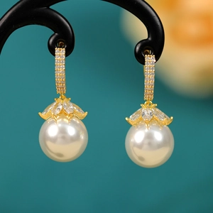 Macro shot of gold pearl drop earrings with sparkling zircon pave settings for elegant style