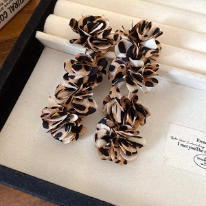 Detail of leopard print fabric flower earrings displayed on a beige velvet jewelry tray