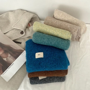 Stack of colorful soft wool blend scarves in neutral tones for winter warmth