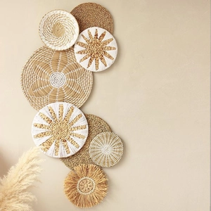 Detailansicht von 8 gewebten Boho-Wandkörben in Naturtönen und Weiß an einer beigen Wand