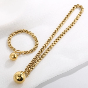 Detailed view of the chunky gold wheat chain necklace set with T-bar clasp and sphere charm