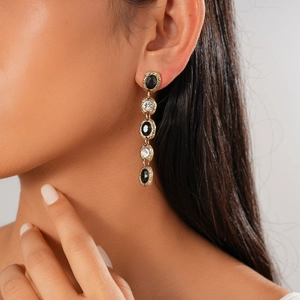 Elegant gold drop earrings with oval black and white crystals on a fashion model