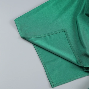 Dettaglio dell'orlo del vestito verde smeraldo con cuciture di pregio e texture liscia